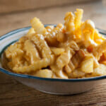 Cheese fries in a bowl on a wooden counter.