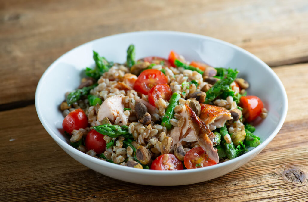 Roasted salmon grain bowl on a wooden counter.