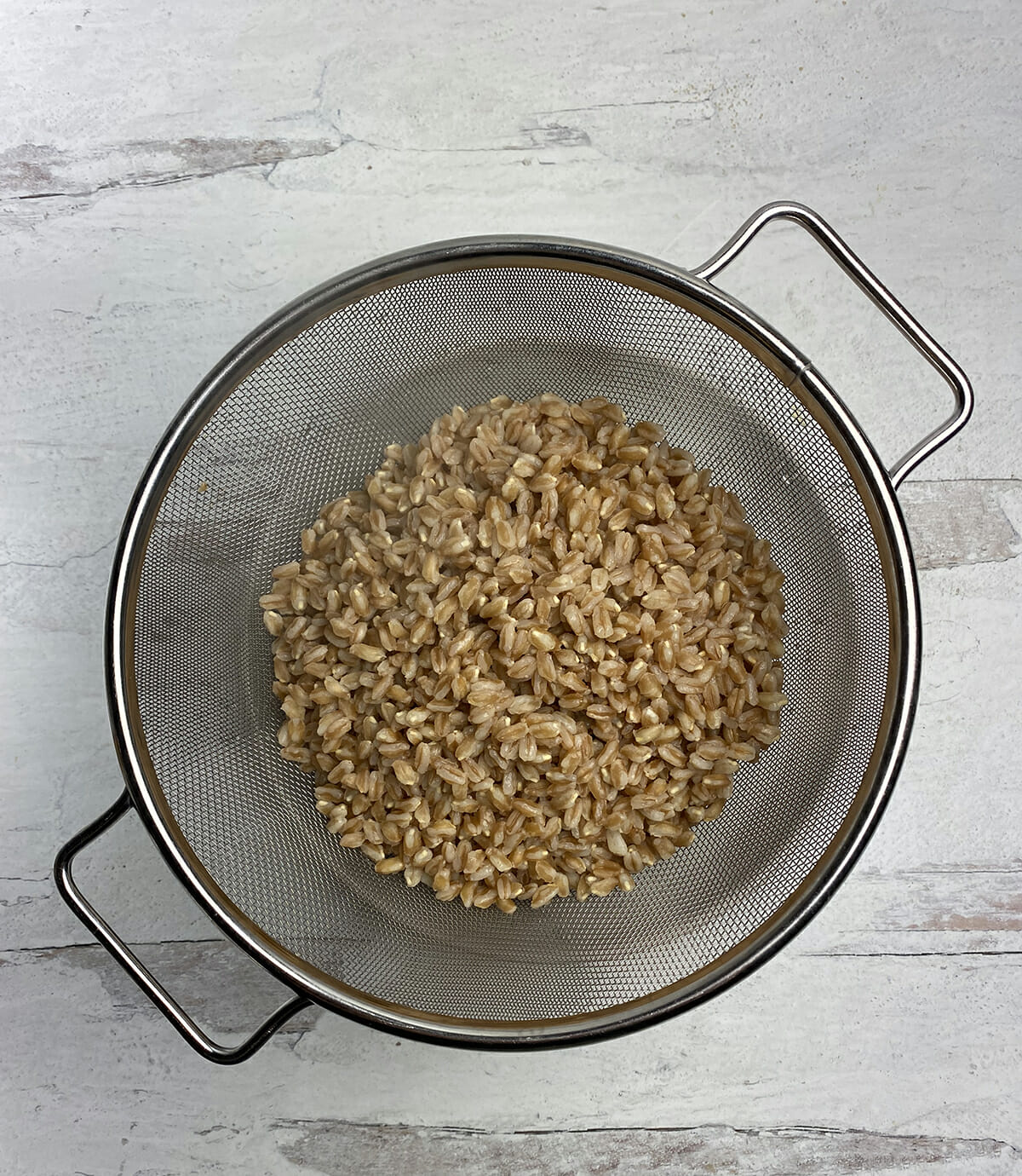 Cooked farro draining in a strainer.