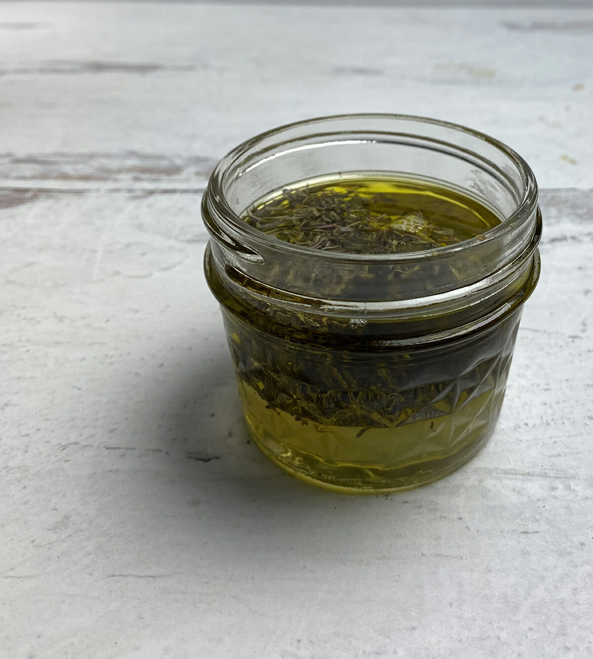 Lemon and olive oil dressing in a small jar ready to pour on the roasted salmon bowl.