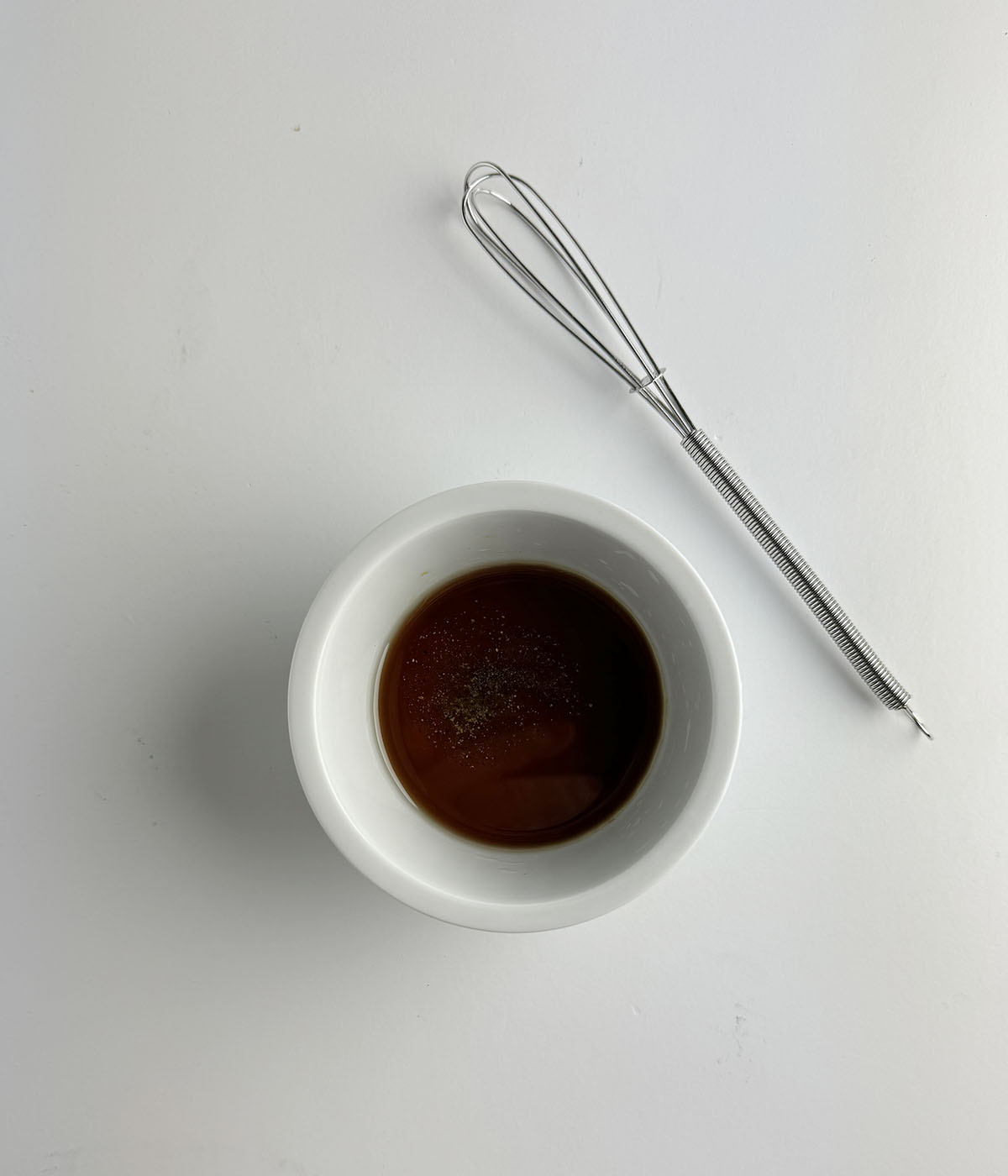 Vinegar sauce in a bowl with a whisk.