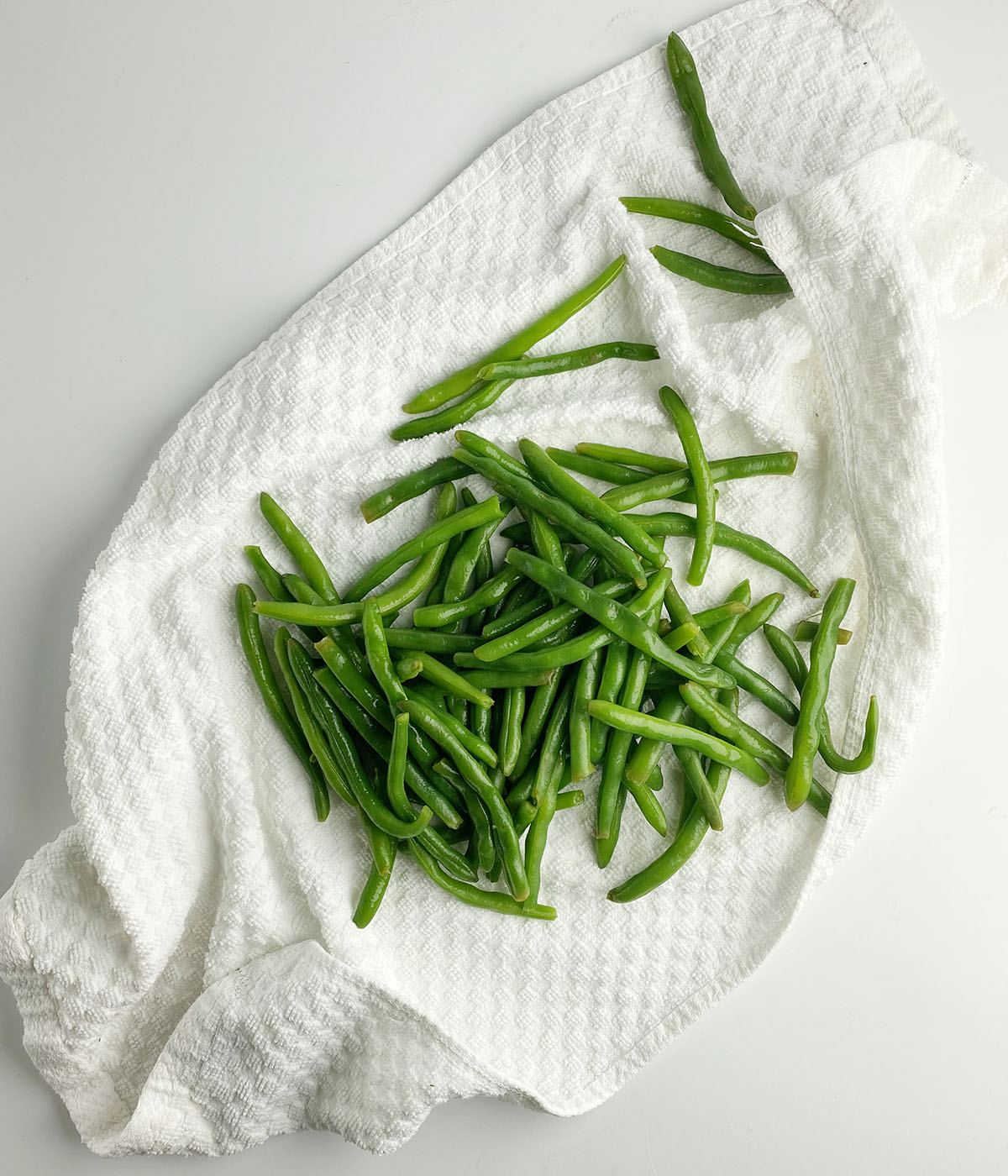 Green beans drying on a dishtowel.