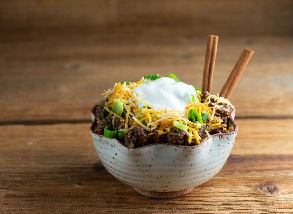 Easy Cinnamon Chili in a bowl on a wooden counter.