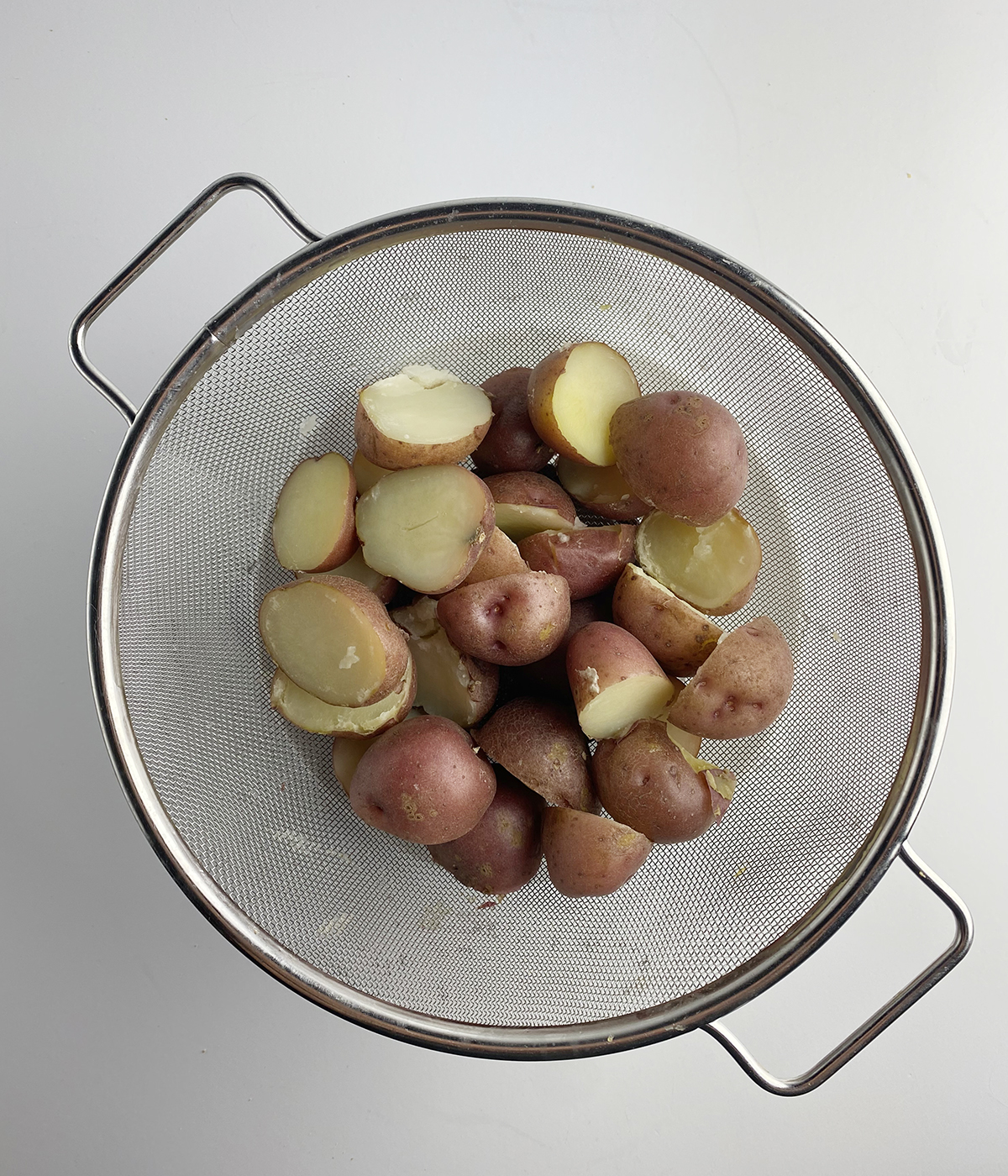 Cooked baby potatoes in a strainer.