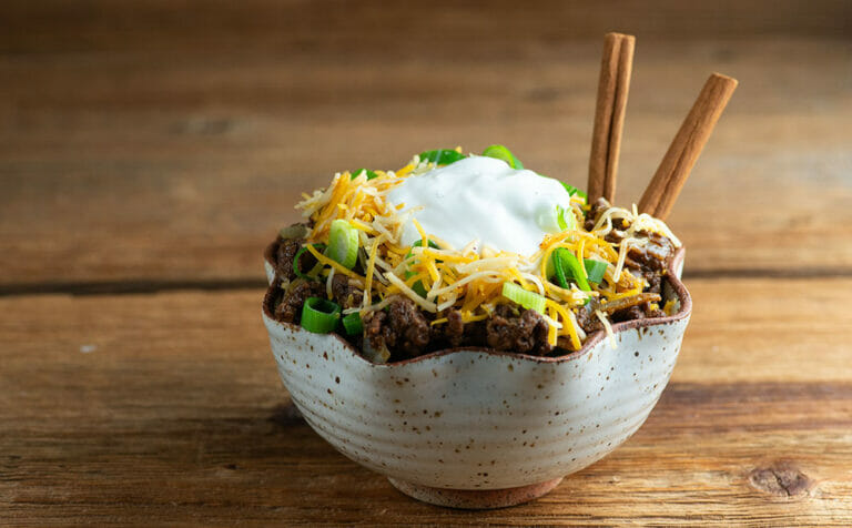 Easy Cinnamon Chili in a bowl on a wooden counter.