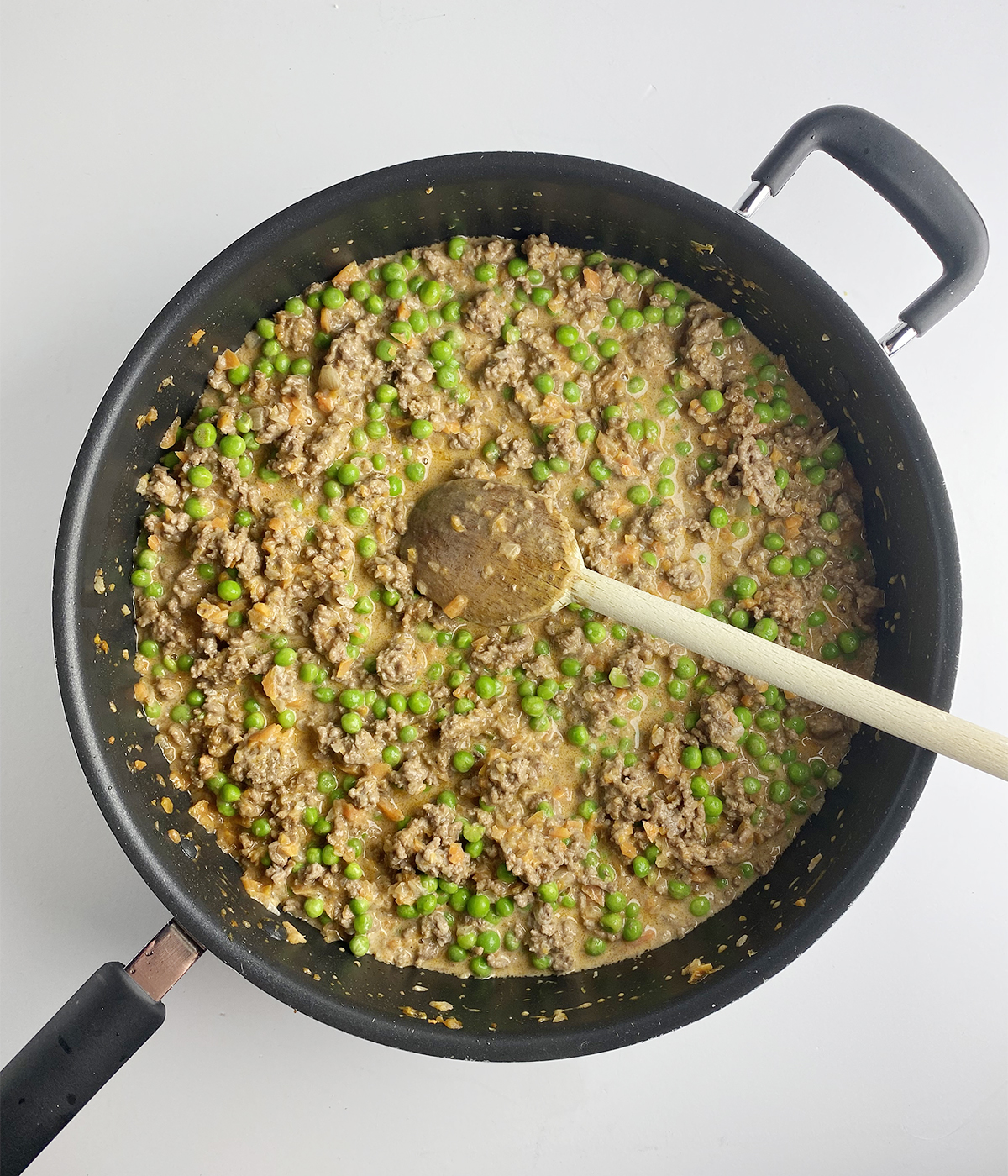 Ground beef and peas mixture in a skillet.