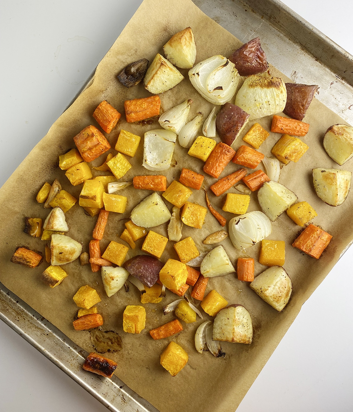 Roasted fall vegetables on a baking pan lined with parchment paper.