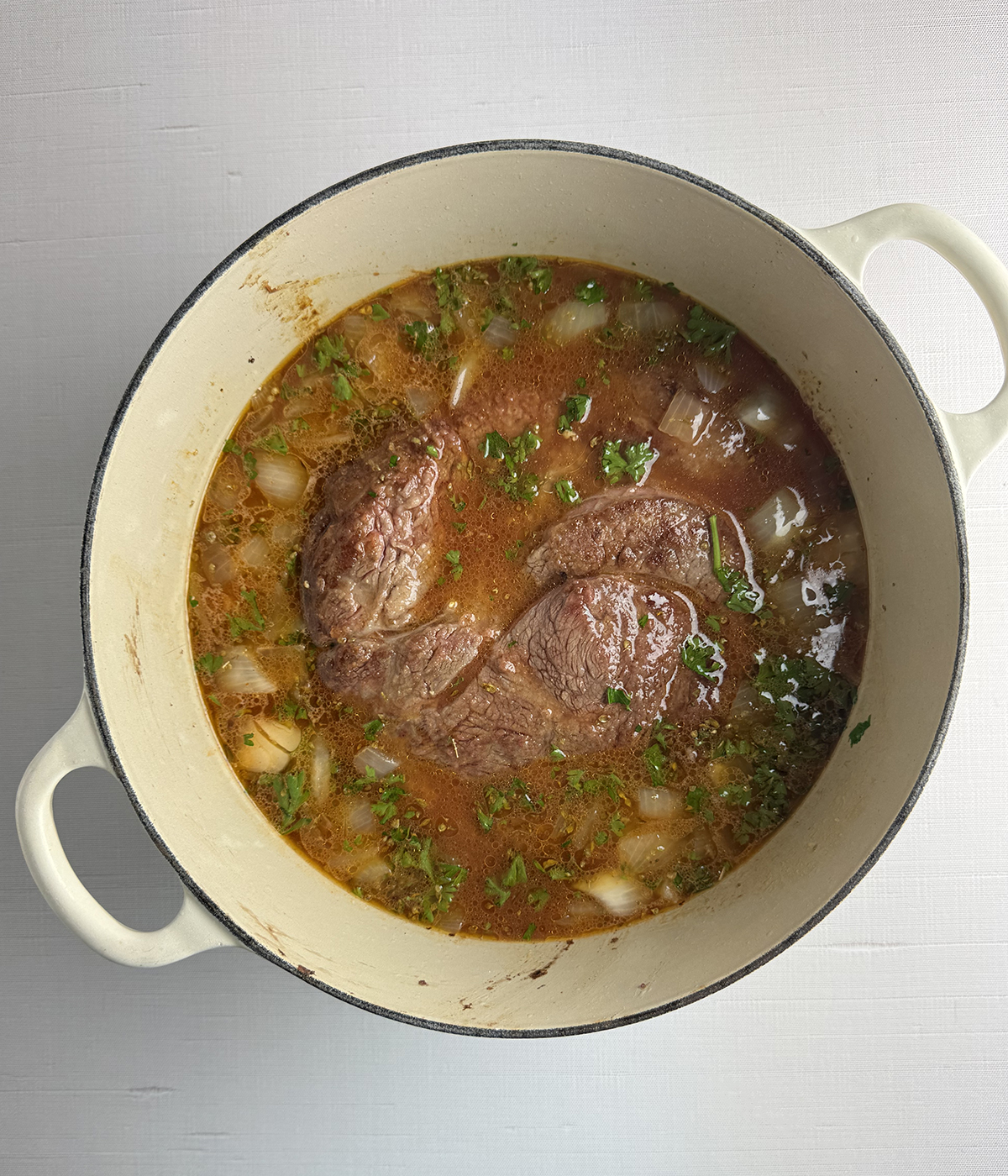 Seared pot roast in broth in a Dutch Oven.