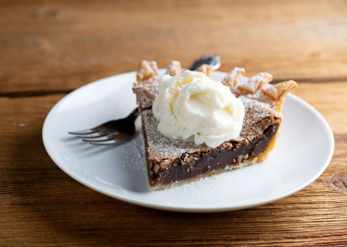 A piece of chocolate chess pie on a plate with a fork.