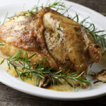 Roasted turkey breast on a platter with herbs.