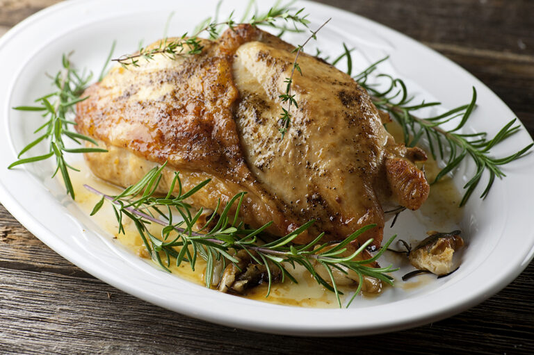 Roasted turkey breast on a platter with herbs.
