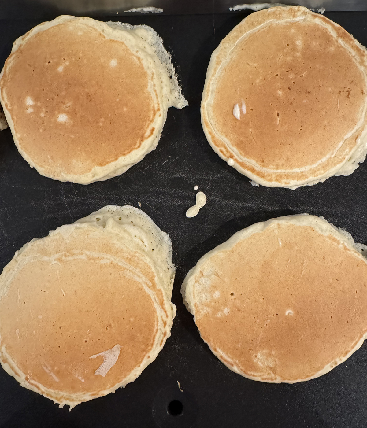 Pancakes cooking on a griddle.