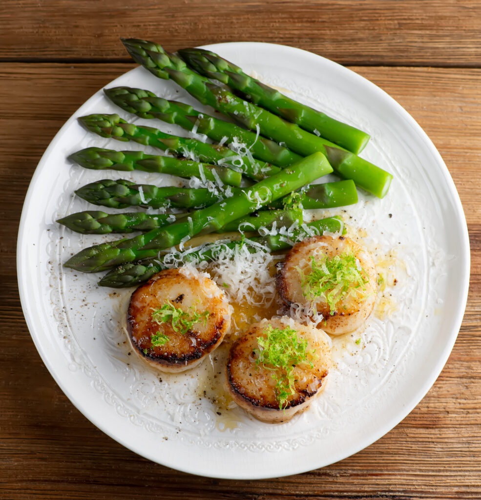 Lime parmesan scallops on a plate with asparagus.