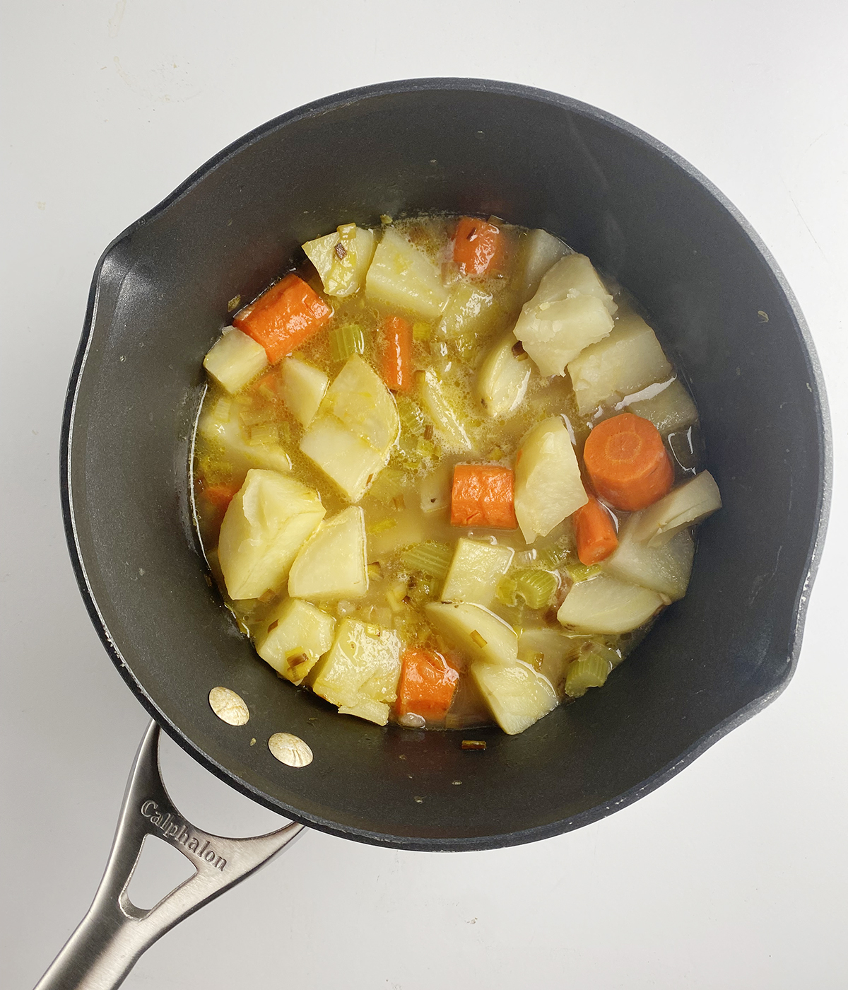 Cooked vegetables in a pot with broth.