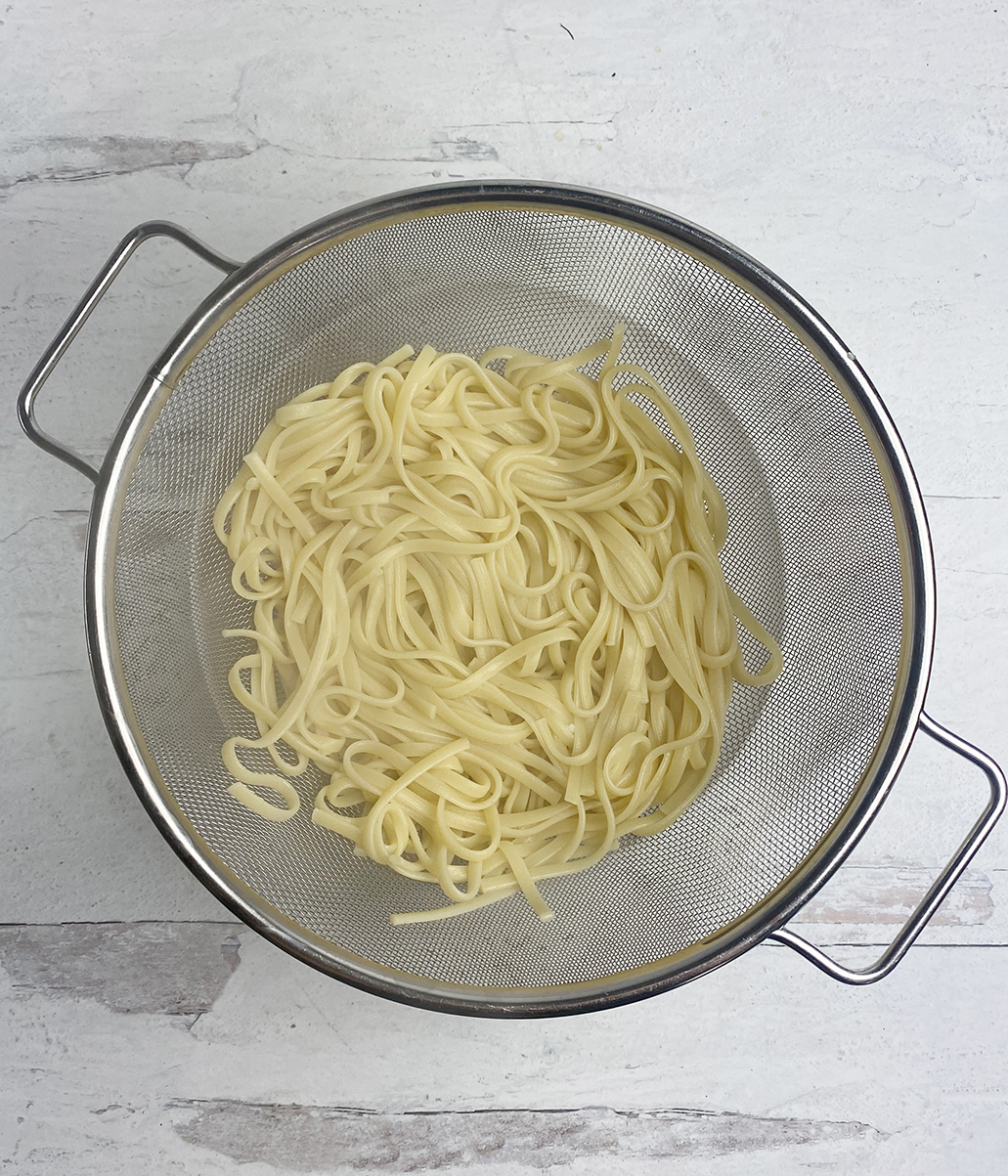 Pasta draining in a strainer.