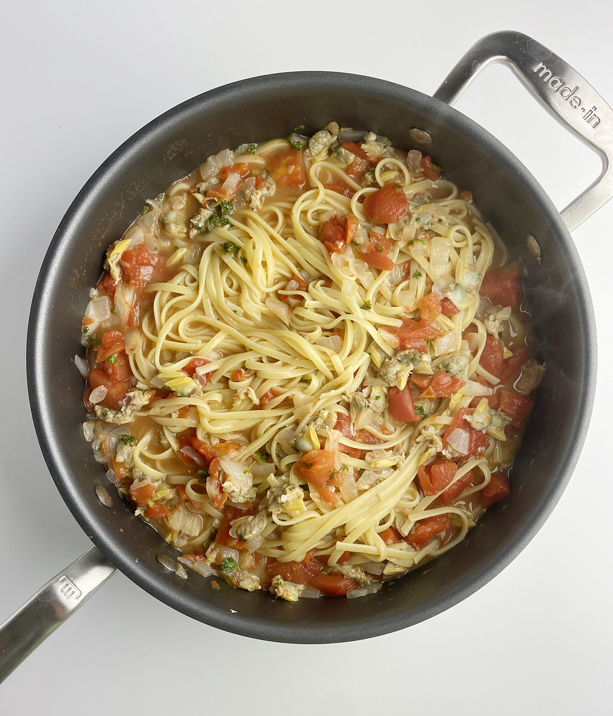 Pasta with finished clam marinara sauce in a skillet.