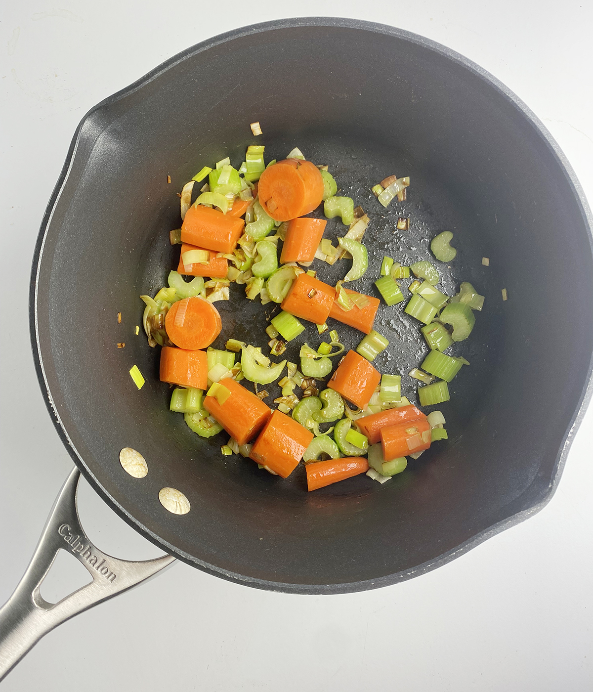 Sauteed carrots, leeks and celery in a pot.