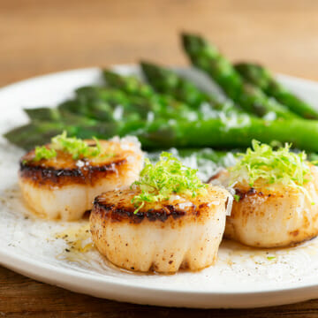 Lime parmesan scallops on a plate with asparagus.