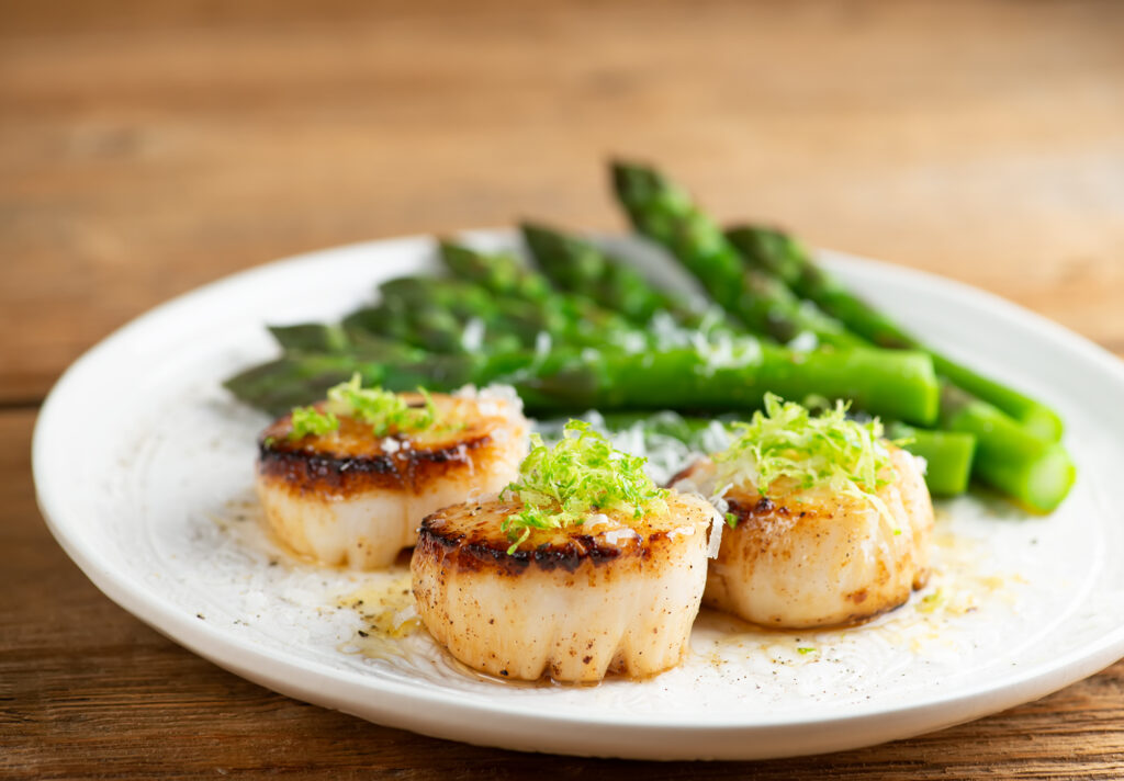 Lime parmesan scallops on a plate with asparagus.