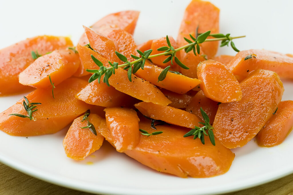 Carrots with fresh thyme on a white plate.