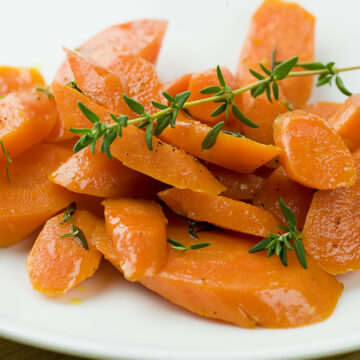 Carrots with fresh thyme on a white plate.