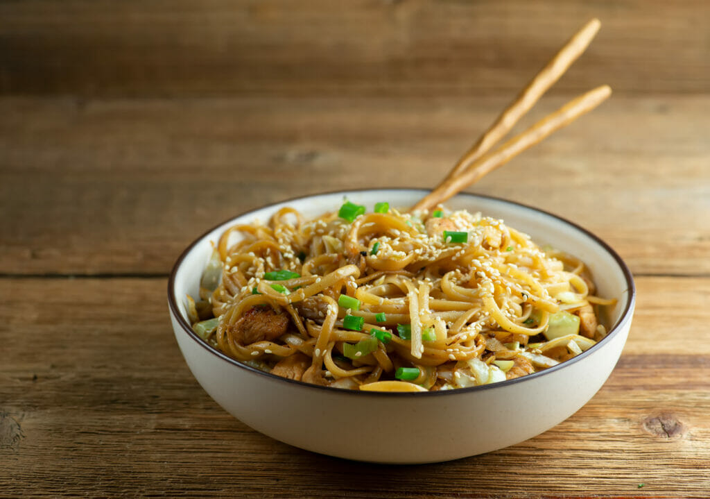 Longevity noodles in a bowl with chopsticks.