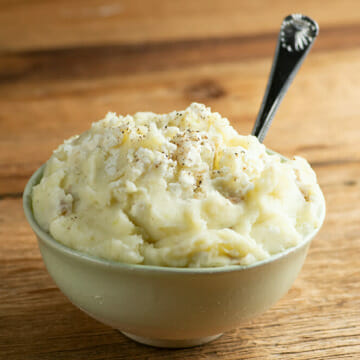 A bowl of creamy feta mashed potatoes with a spoon.