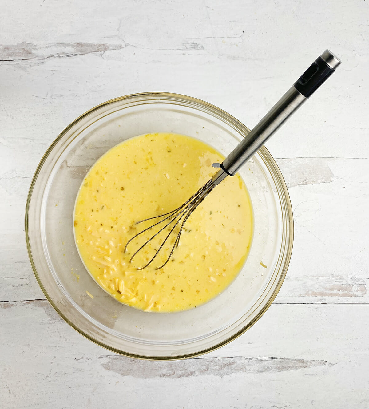 Egg sauce for breakfast ramen in a mixing bowl with a whisk.