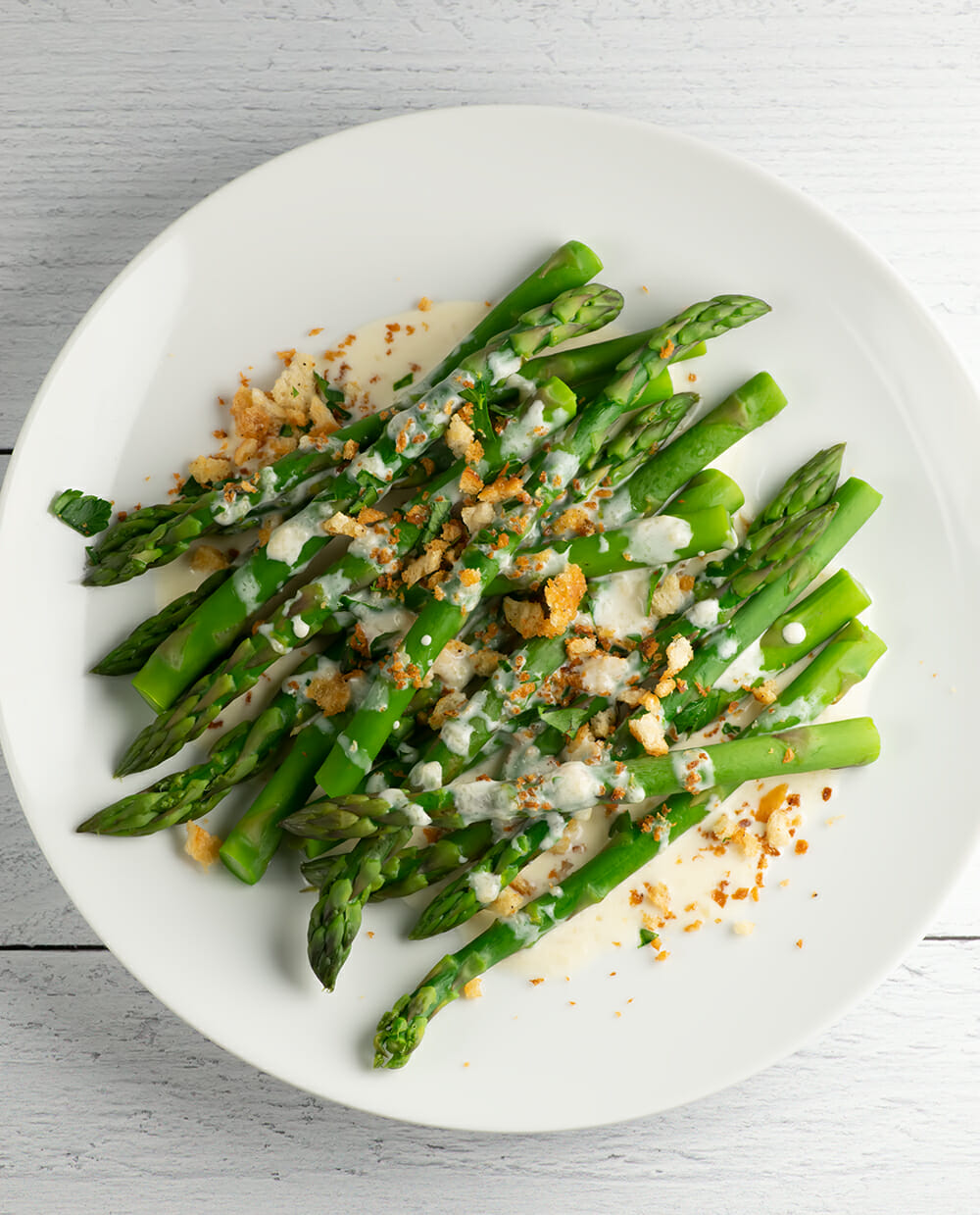 asparagus with parmesan and breadcrumbs on a white plate breadcrumb sauce