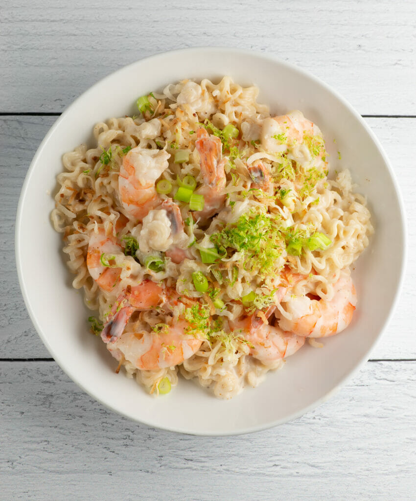 Coconut shrimp ramen in a bowl on a wooden counter.