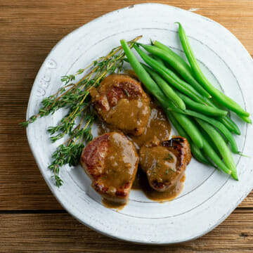 Pork Medallions with Buttered Mustard Sauce on a plate with green beans.