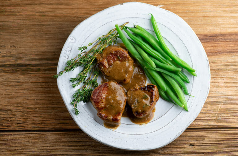 Pork Medallions with Buttered Mustard Sauce on a plate with green beans.