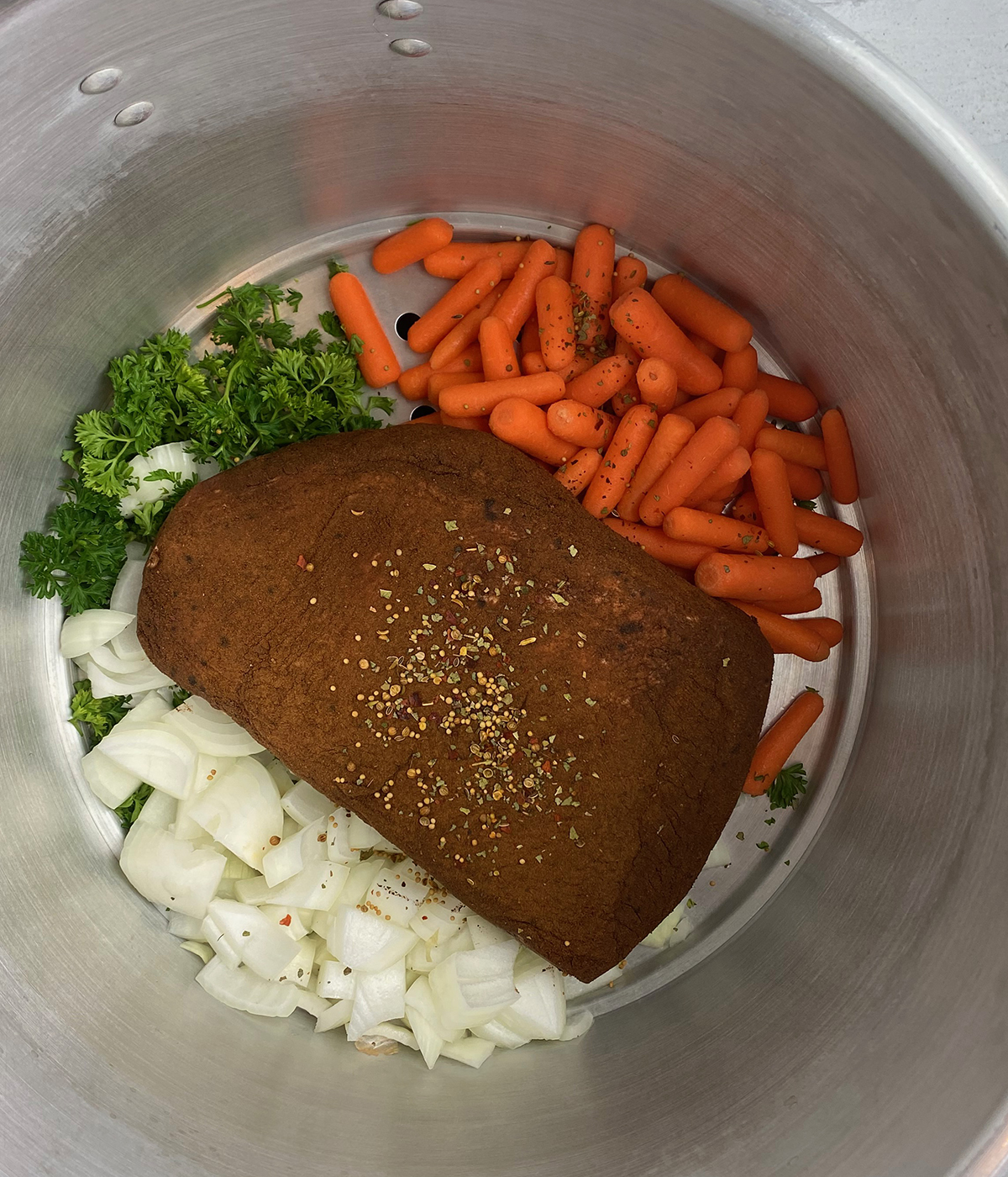 Corned beef in a pot with veggies ready for cooking.