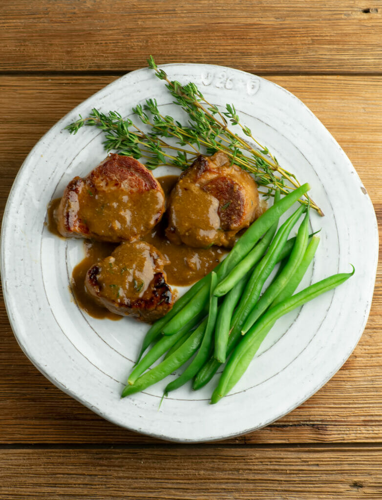 Pork Medallions with Buttered Mustard Sauce on a plate with green beans.