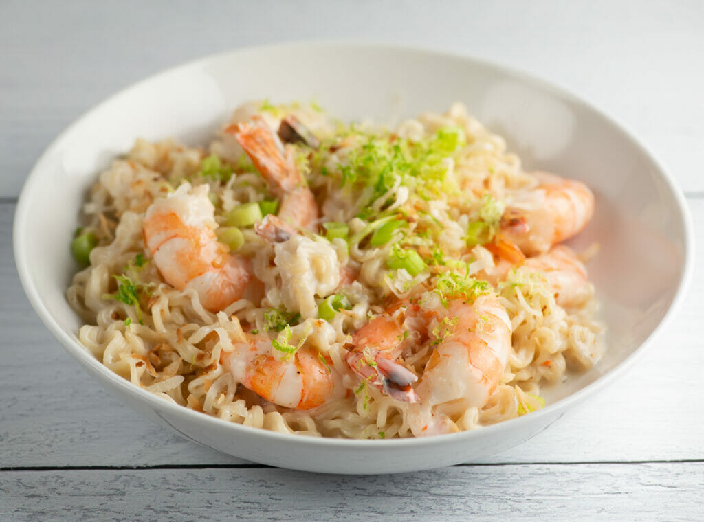 Coconut shrimp ramen in a bowl on a wooden counter.