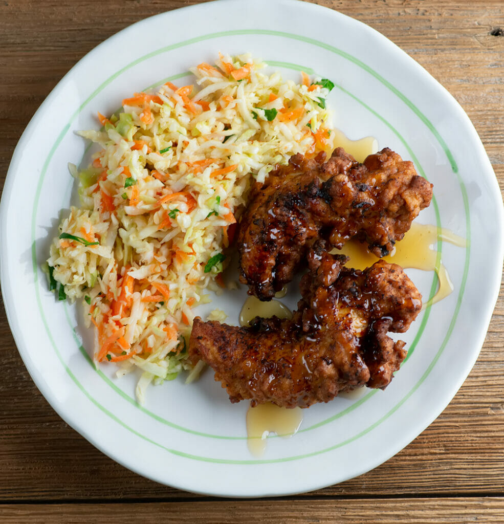 Honey fried chicken tenders with coleslaw on a plate.