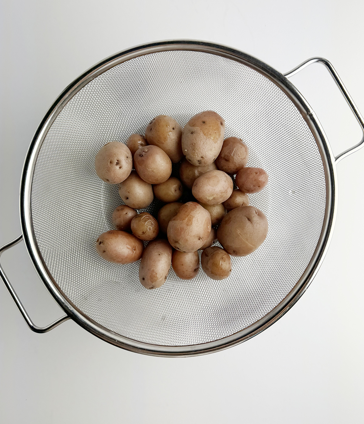 Cooked baby potatoes in a strainer.