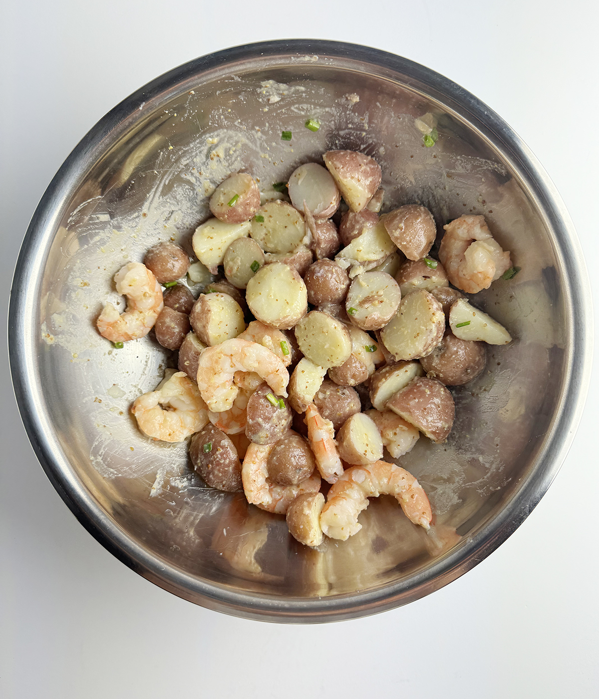 Shrimp and baby potato salad in a metal mixing bowl.
