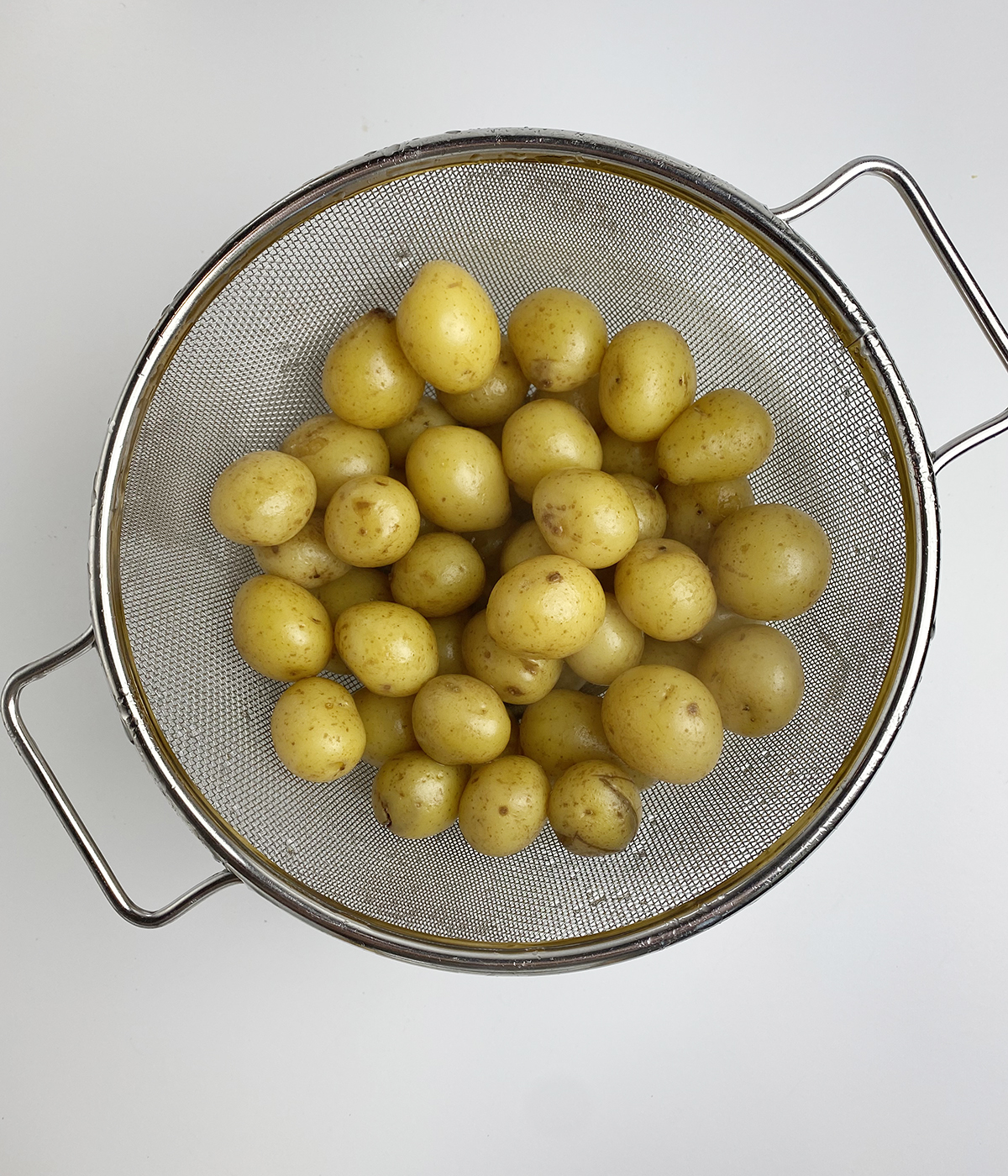 Cooked baby potatoes in a strainer.