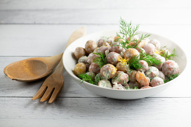 Sour cream potato salad in a bowl with serving utensils.
