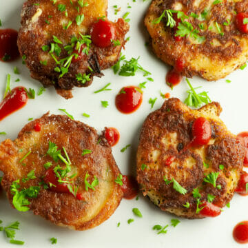Clam fritters with hot sauce and parsley on a plate.
