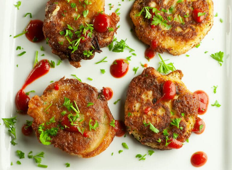 Clam fritters with hot sauce and parsley on a plate.