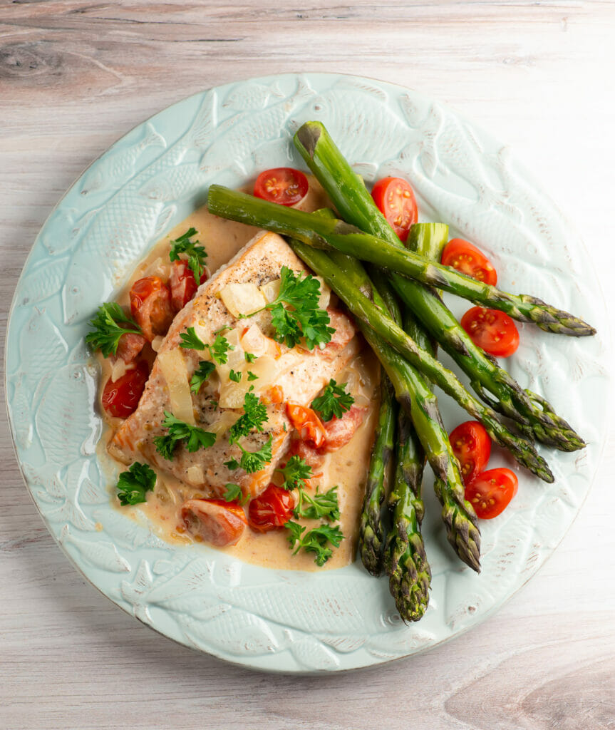 Easy roasted salmon with creamy tomato sauce on a plate.