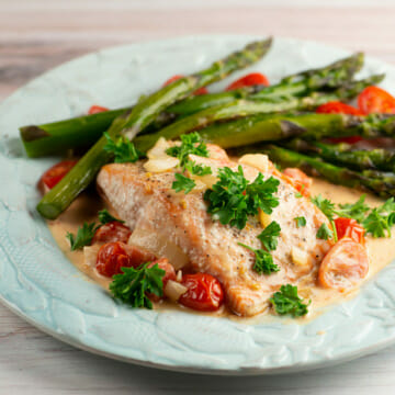 Roasted salmon with creamy tomato sauce on a plate.