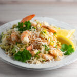 Coconut shrimp salad on a plate with lemons.