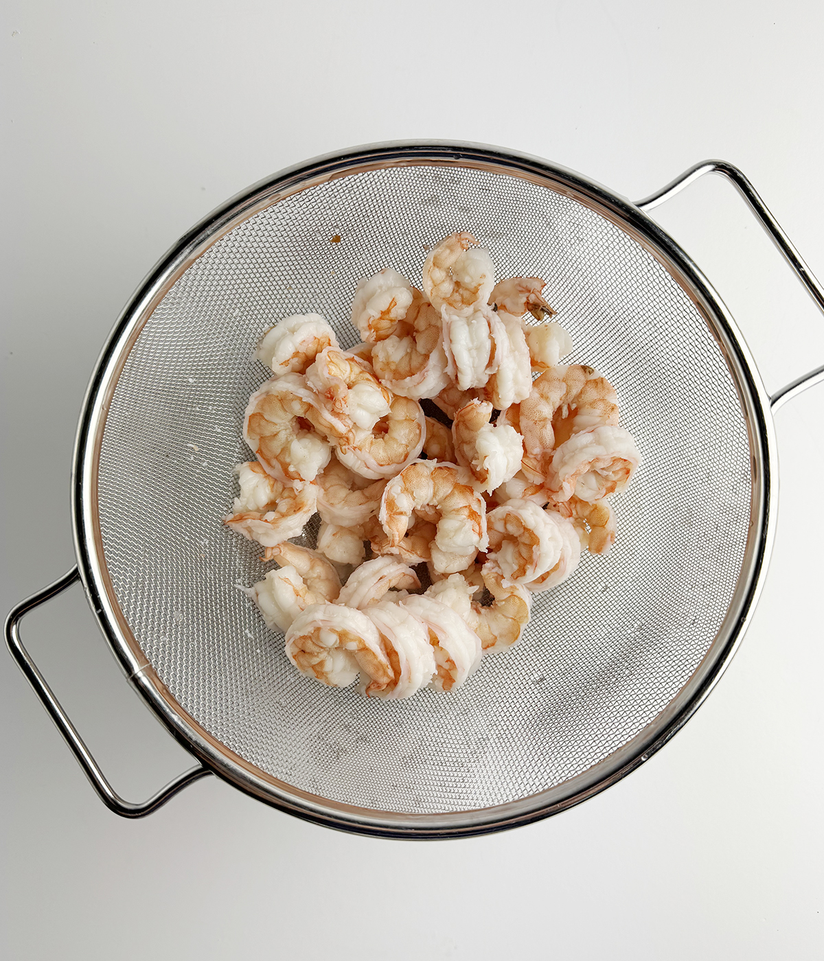 Cooked shrimp in a strainer.