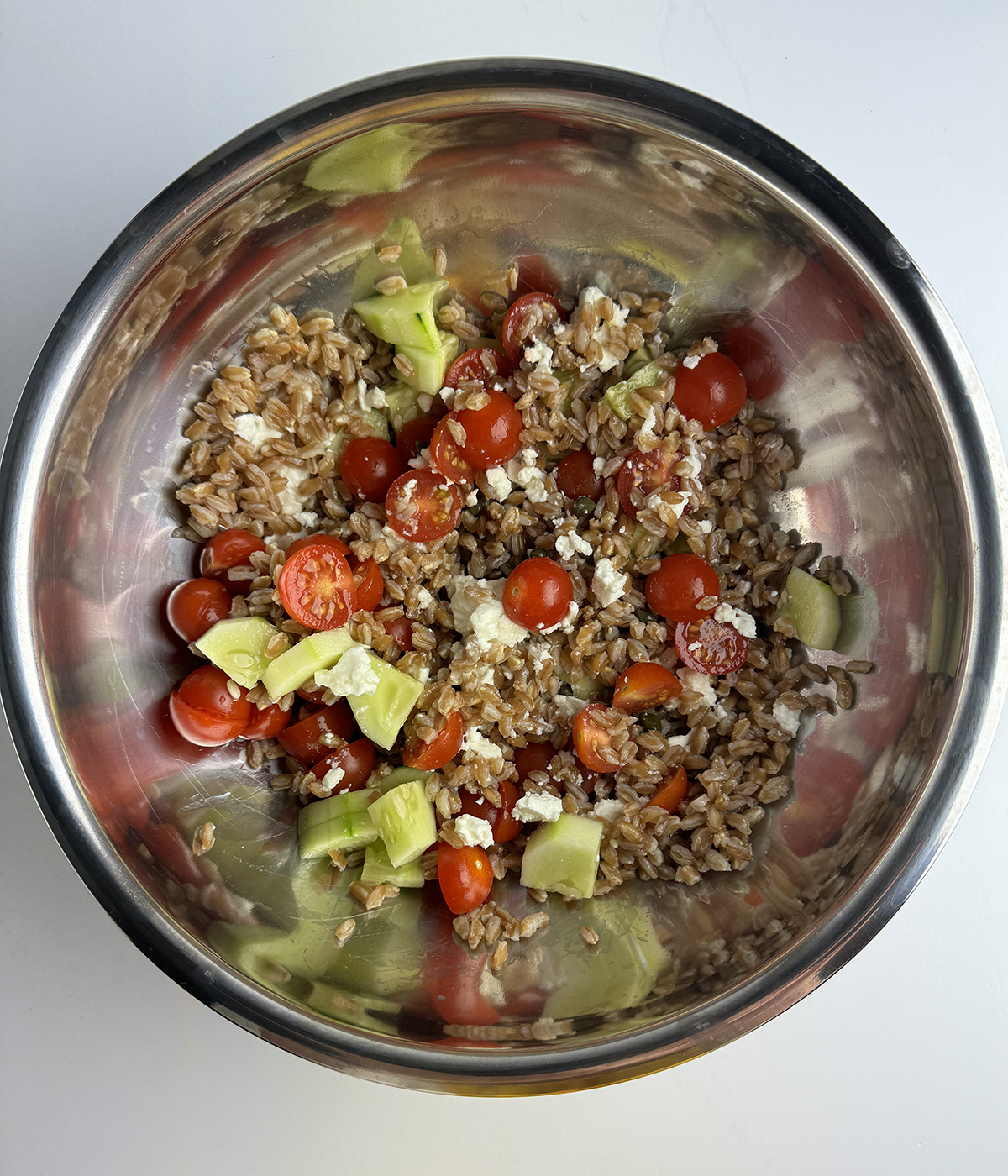 Grain salad with veggies in a mixing bowl.