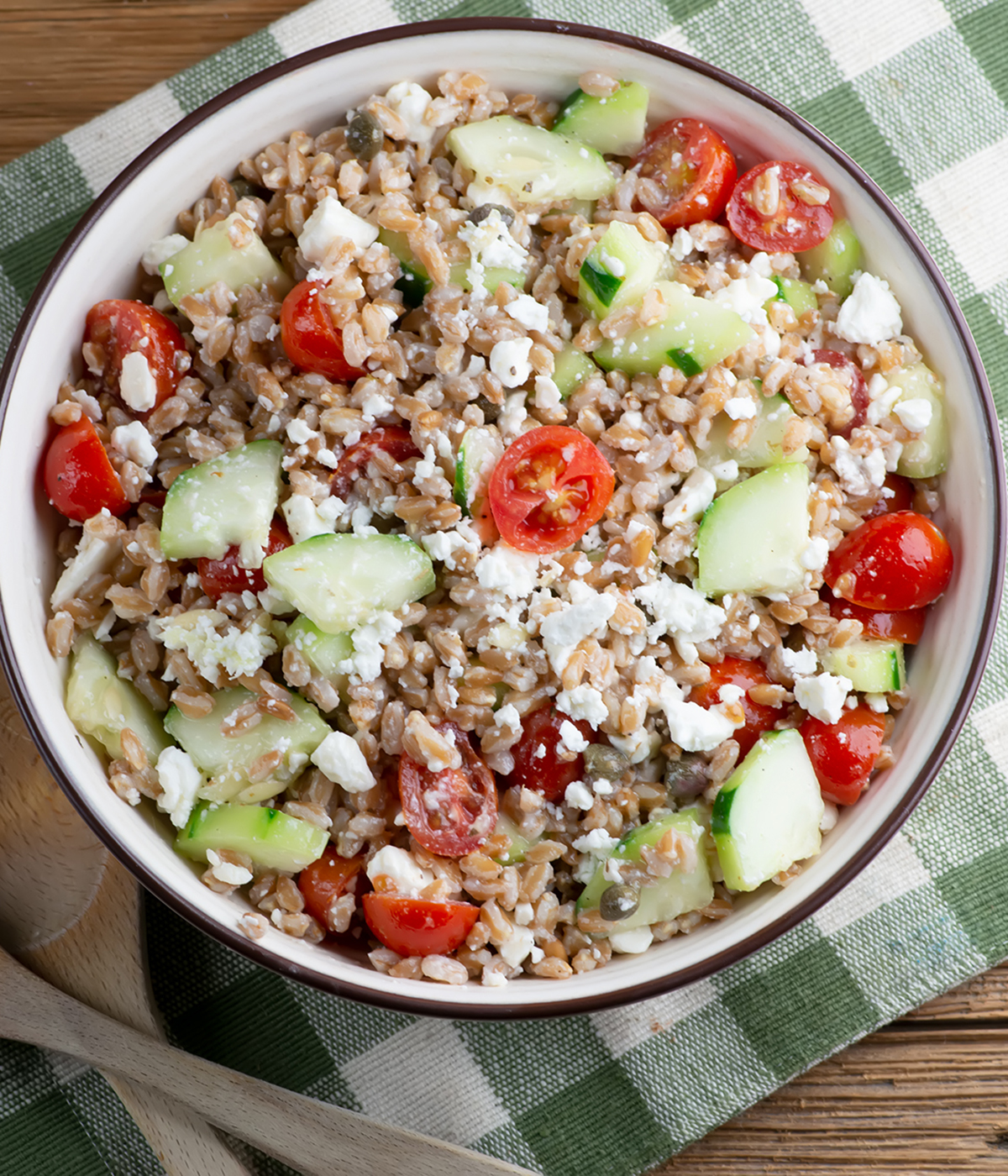 Greek grain salad in a bowl on a dishtowel.