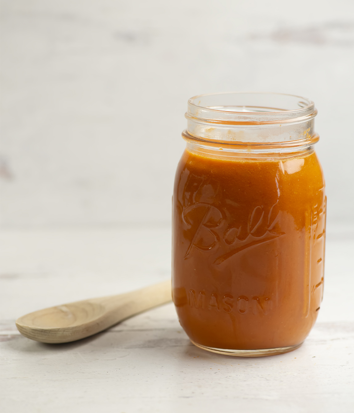 Homemade tomato sauce in a mason jar with a wooden spoon.