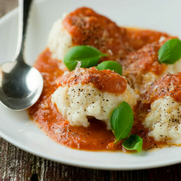 Ricotta dumplings with tomato sauce on a plate with a spoon.